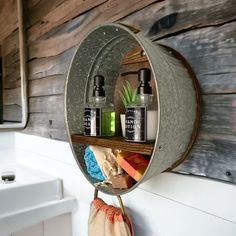 a metal bucket with some bottles in it on a shelf next to a sink and mirror