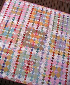 a multicolored quilt on a wooden deck