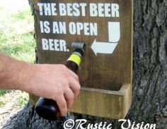 a man is opening a beer bottle in front of a sign that says the best beer is an open beer