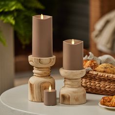 three candles sitting on top of a table next to bread and croissants