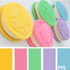 there are some cookies on the plate with different colors in front of it and an orange, yellow, green, blue, pink, purple, and white color scheme