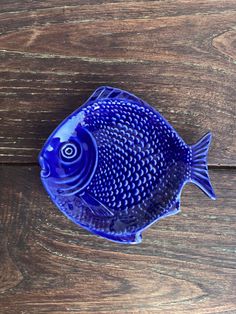 a blue glass fish sitting on top of a wooden table