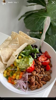 a white bowl filled with taco salad and tortilla chips on top of it