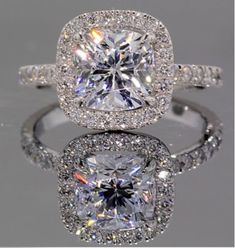 an engagement ring with a cushion cut diamond surrounded by pave diamonds and halos