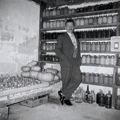 a man in a suit standing next to shelves full of jars