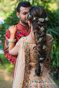 a man and woman standing next to each other with their arms around each other, both wearing