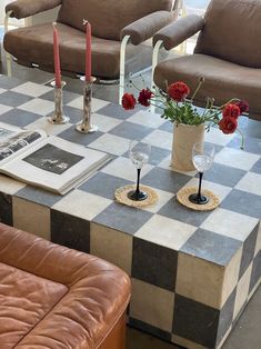 a checkered table with candles and flowers in vases sitting on top of it