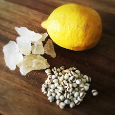 an orange sitting on top of a wooden cutting board next to some nuts and salt