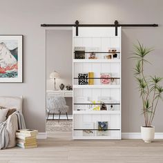 a living room with a white book shelf next to a plant