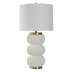 a white lamp with a gold base and a white shade on the top of it