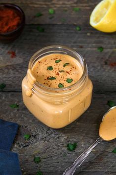 a glass jar filled with mustard and garnished with parsley next to two spoons