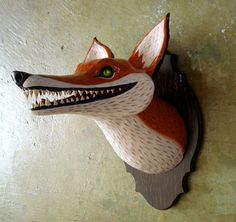 an animal head mounted to the side of a wall with its mouth open and teeth wide