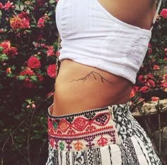 a woman's stomach with tattoos on it and the words mountains written in black ink