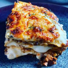 a blue plate topped with lasagna covered in cheese