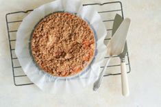 a pie sitting on top of a cooling rack next to a knife and spoons