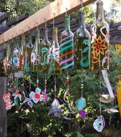 several wine bottles are hanging from a wooden structure in front of some bushes and trees