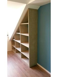 an empty bookcase in the corner of a room with blue walls and wooden floors