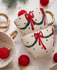 three white cups decorated with red bows and christmas decorations