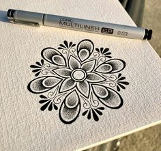 a pen is sitting on top of a paper with a drawing in the center and an intricate design