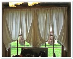 a kitchen window covered in white curtains