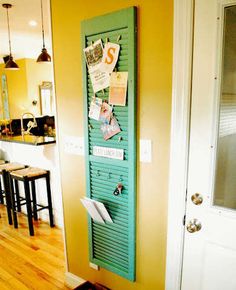 a green door that has some papers on it in front of a kitchen with stools