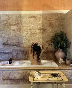 a woman sitting in a bath tub next to a table with utensils on it