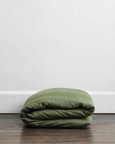 a green pillow sitting on top of a wooden floor next to a white painted wall