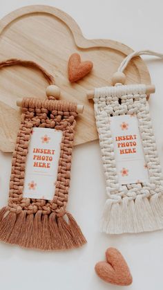 two wooden frames with tassels and hearts next to them on a white surface