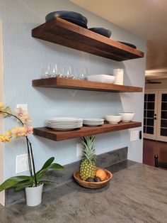 a kitchen counter with plates and bowls on top of it next to a pineapple