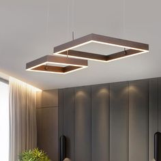 an overhead light fixture in a modern kitchen with wooden cabinets and potted plant on the counter