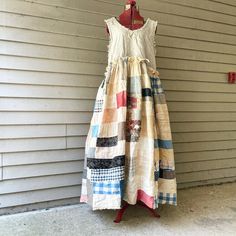 a dress made out of old clothing hanging on a hanger in front of a house