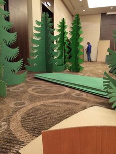 an office lobby decorated with paper cut trees and people standing in the background looking at them