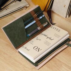 three notebooks with pens in them on a table next to papers and other items