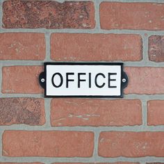 a brick wall with a sign on it that says office written in black and white