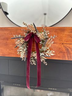 a wreath hanging on the front door of a house with a red ribbon tied around it