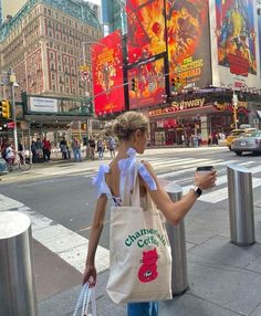 a woman walking down the street with a bag and cell phone in her hand,