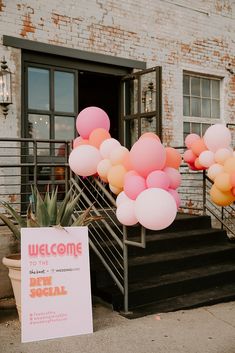 a welcome sign and balloons in front of a brick building with stairs leading up to it