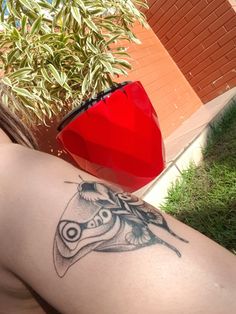 a man with a tattoo on his arm next to a red vase and green grass