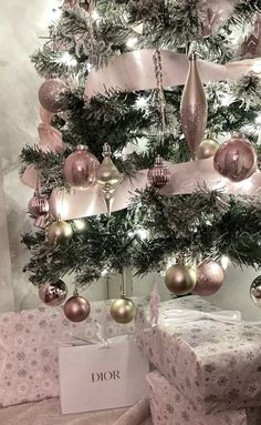 a christmas tree with presents under it and lights on the top is decorated in pink, gold and silver