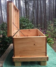 a wooden box sitting on top of a green blanket in the middle of a forest