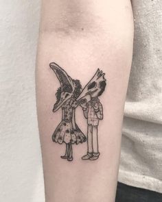 a man and woman tattoo on the left arm with two birds holding each other's beaks