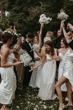 a group of people standing around each other holding bouquets and throwing confetti in the air