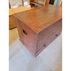 a wooden box sitting on top of a floor next to a table and chair in a room