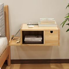 a nightstand with books and magazines on it next to a bed