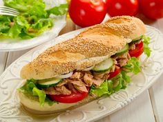 a sandwich with meat, lettuce and tomatoes on a plate next to salad