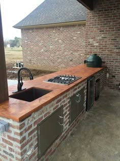 an outdoor kitchen made out of brick and steel with a grill on the counter top