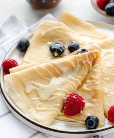 three crepes on a plate with berries and blueberries next to each other