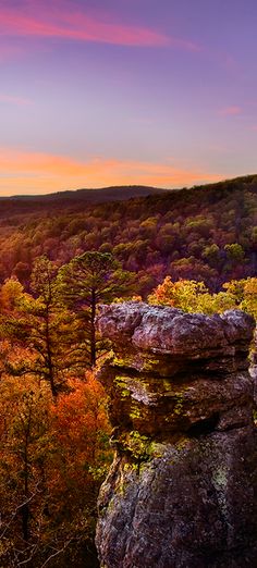 the sun is setting over some trees and rocks