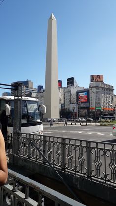 a woman standing on the side of a bridge next to a tall obelisk