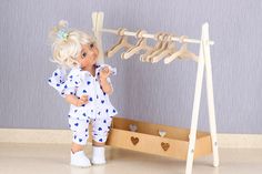 a doll is standing next to a clothes rack